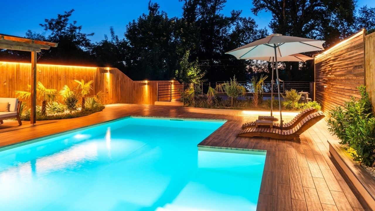 Infinity swimming pool at night with illuminated water and lounge chairs at Forbes Fab Luxe